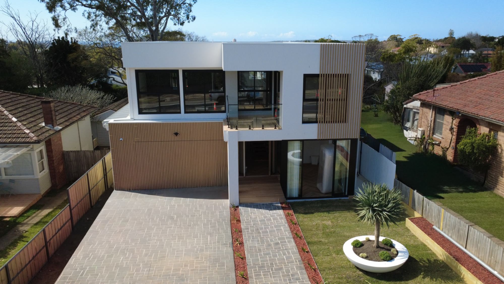 Aerial view of the front elevation of a completed custom home on Sydney's Northern Beaches, showing the house, driveway and garden from above